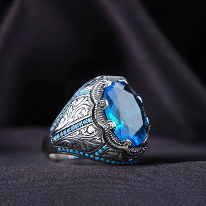 Close-up of a blue zircon geometric grandmother ring in antique silver on a finger.