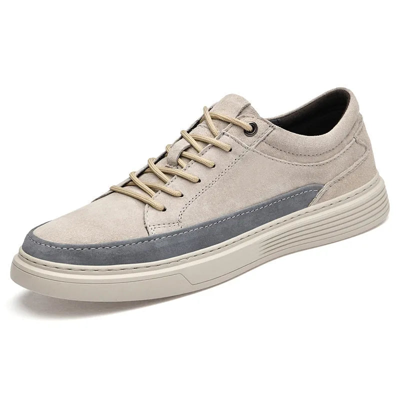 Men's grey low-top casual leather skate shoes with round toe and flat rubber sole on a wooden surface.