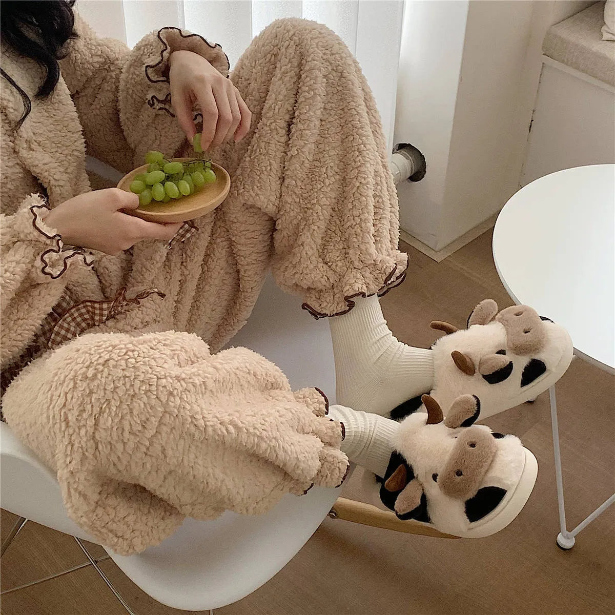 White cow-themed plush slippers with a non-slip textured sole for women.