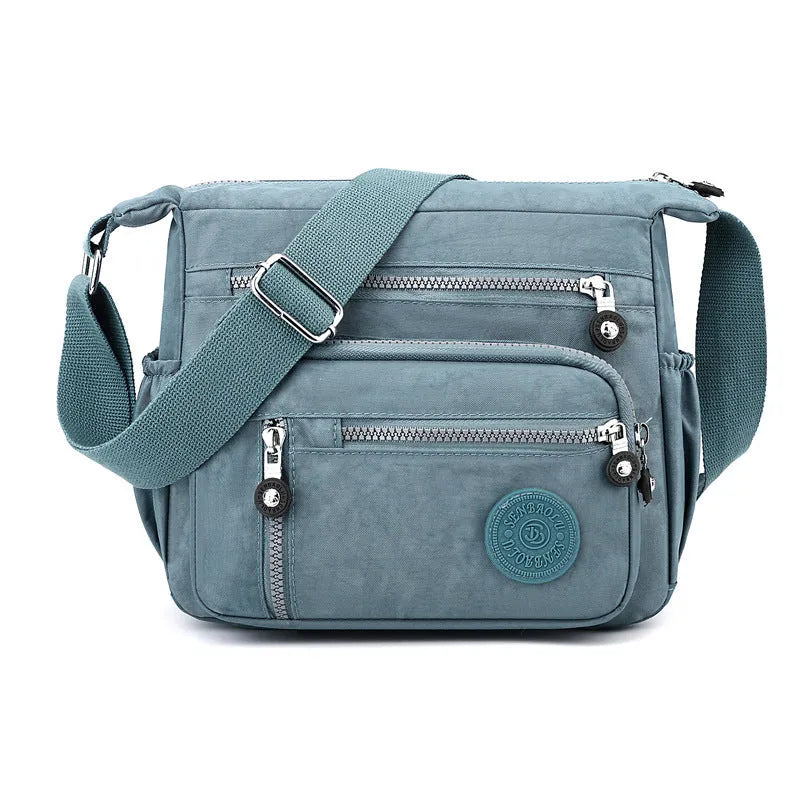 Soft grey nylon messenger bag with a single shoulder strap, shown in a square vertical shape.