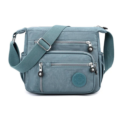 Soft grey nylon messenger bag with a single shoulder strap, shown in a square vertical shape.