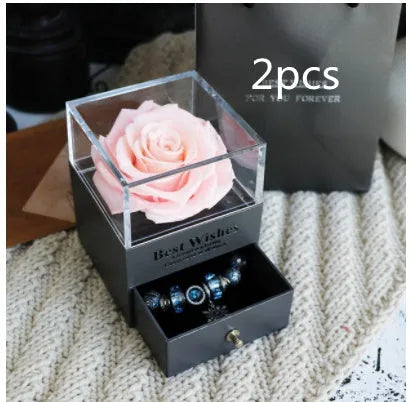 Blue and pink eternal flower gift box with roses and carnations on a table.