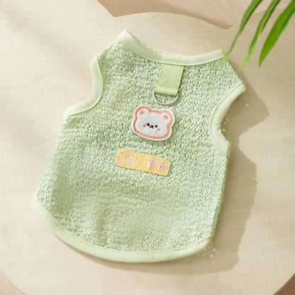 Green knitted cat clothing with a cartoon bear patch, showing hollowed-out breathable design.