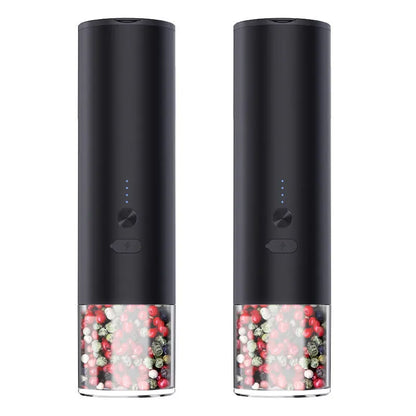 White electric salt and pepper grinder with stainless steel top and clear glass jar on a kitchen counter.