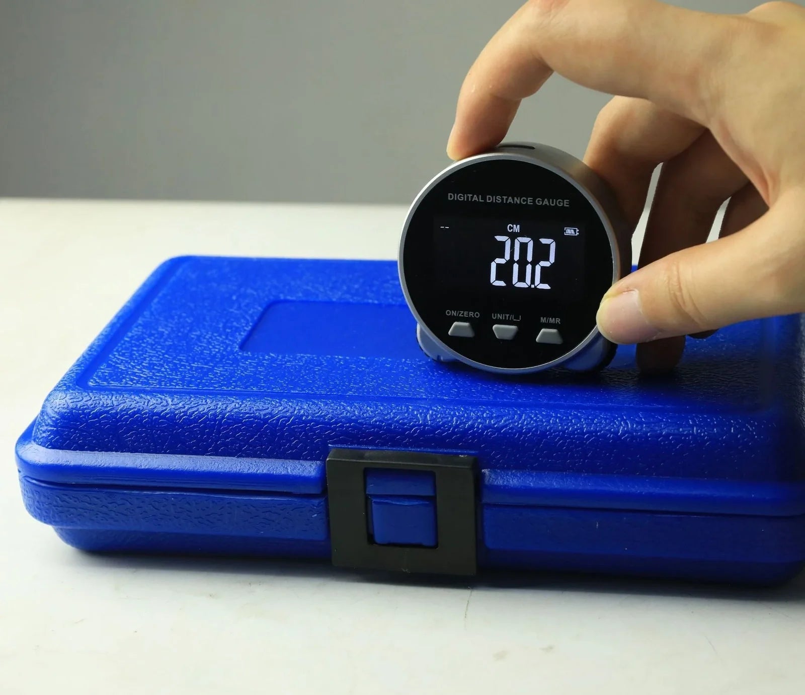 Grey digital rolling measurement tool displaying 200m range on straight surfaces with cm/inch units