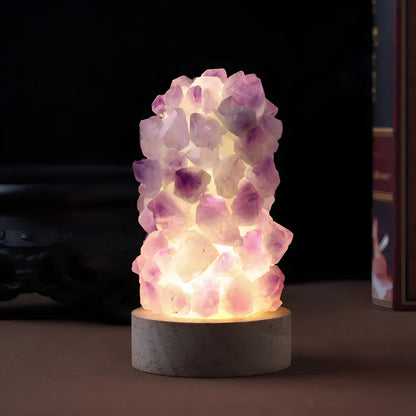 Miniature amethyst crystal tooth flower night light glowing with warm light on a wooden surface.