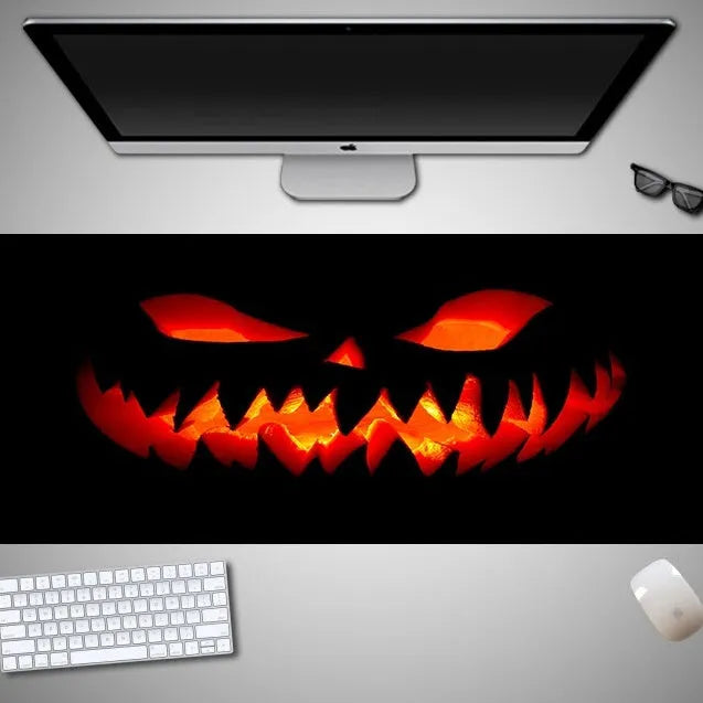 Halloween-themed oversized cloth mouse pad with non-slip rubber base on a wooden desk.