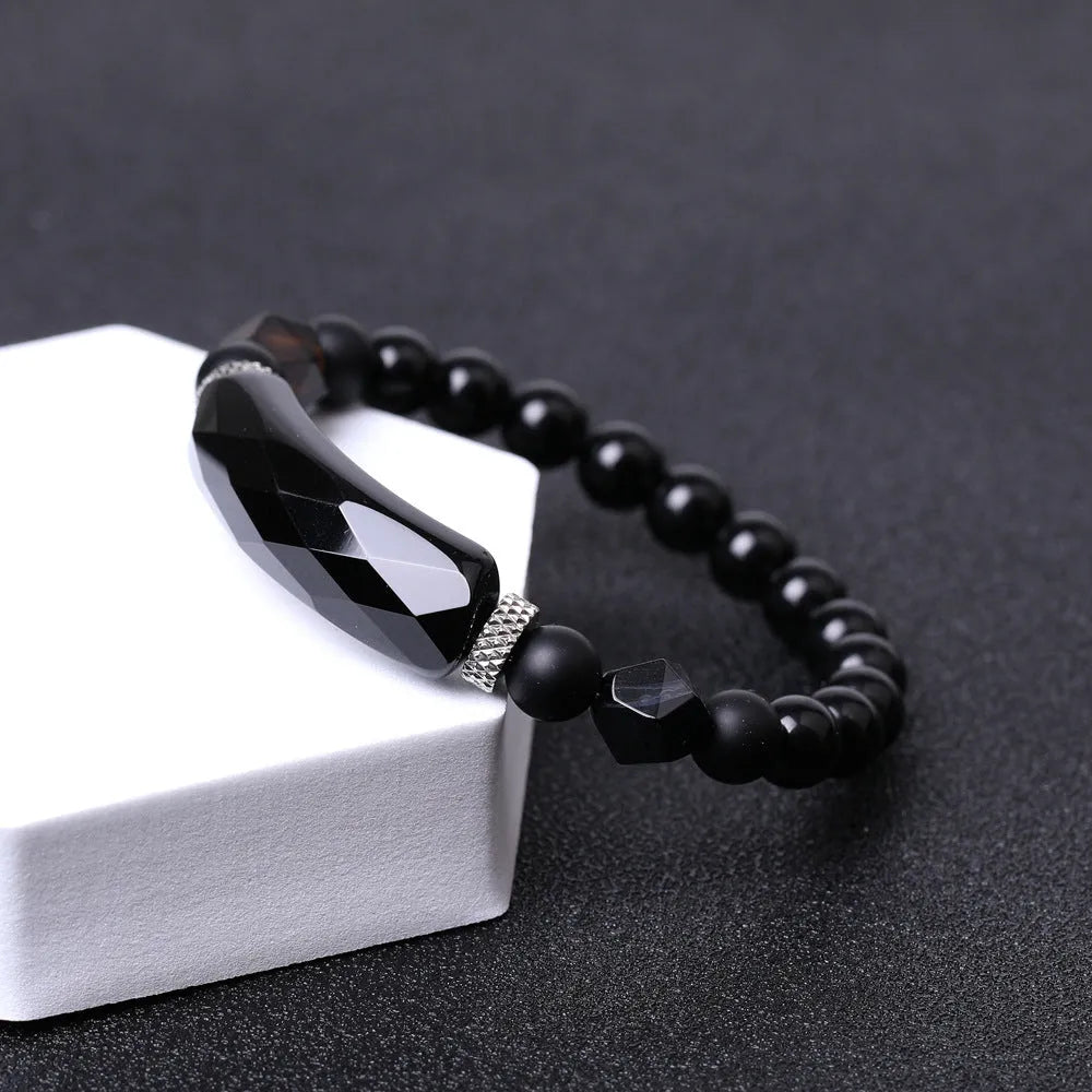 Handmade diamond-shaped cut black agate bracelet with fan-shaped details on a wrist.