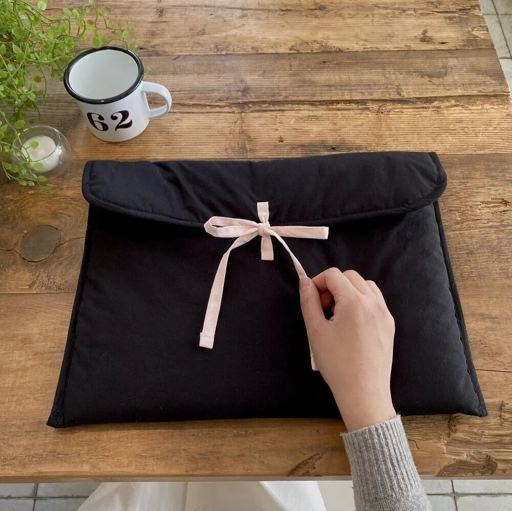 Women's black quilted laptop bag with striped pattern and ballet bow, showing smooth nylon interior