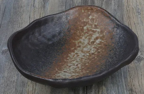 Japanese style irregular shaped ceramic sashimi bowl with floral decoration on table.