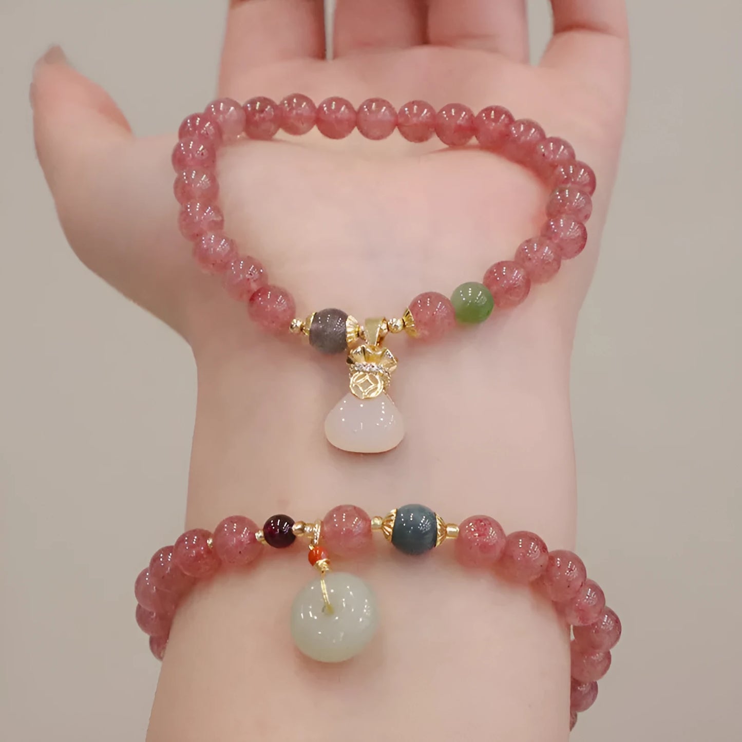 Women's strawberry quartz bracelet with geometric design and decorative purse charm on safety buckle closure