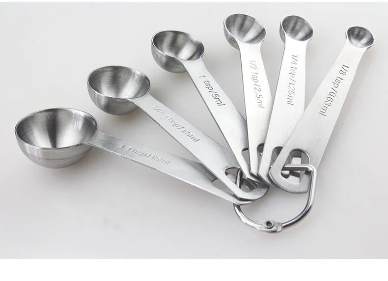 Six stainless steel measuring spoons with engraved markings and D-shape ring, sizes 1/8 tsp to 1 Tbsp