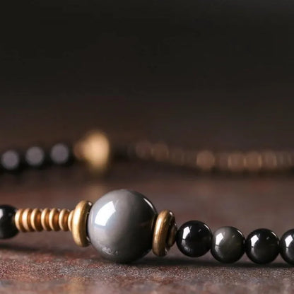 Black geometric layered beaded bracelet shown on a wrist.