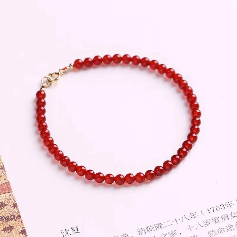 Slim red agate bead bracelet for women on a wrist, classic minimalist jewellery style.