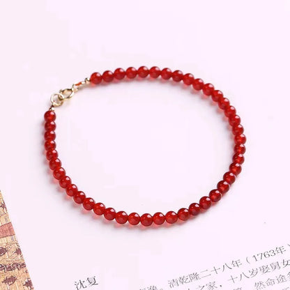 Slim red agate bead bracelet for women on a wrist, classic minimalist jewellery style.