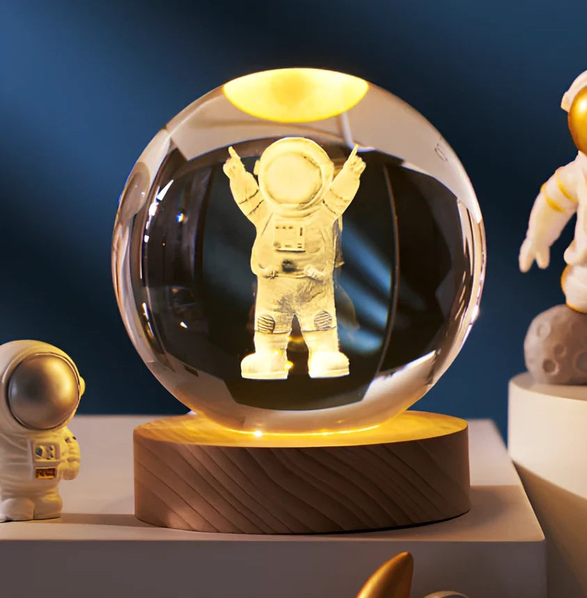 3D crystal ball night light projecting solar system pattern on wooden base with astronaut figurine