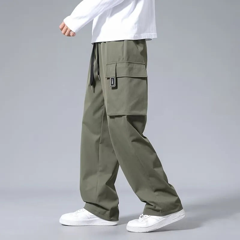 Boys in straight leg cargo trousers with drawstring waist and large side pockets, shown in Army Green.
