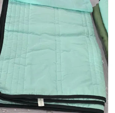 Lightweight plain coloured polyester summer quilt on a bed