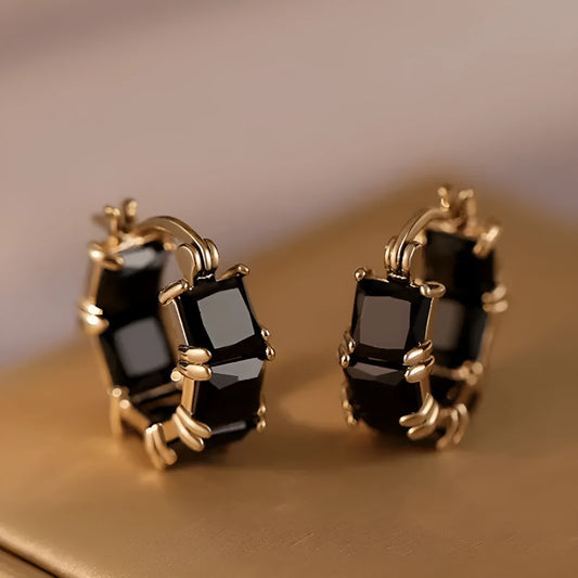 A pair of geometric U-shaped copper earrings with a round zircon stone in a gold-coloured setting.