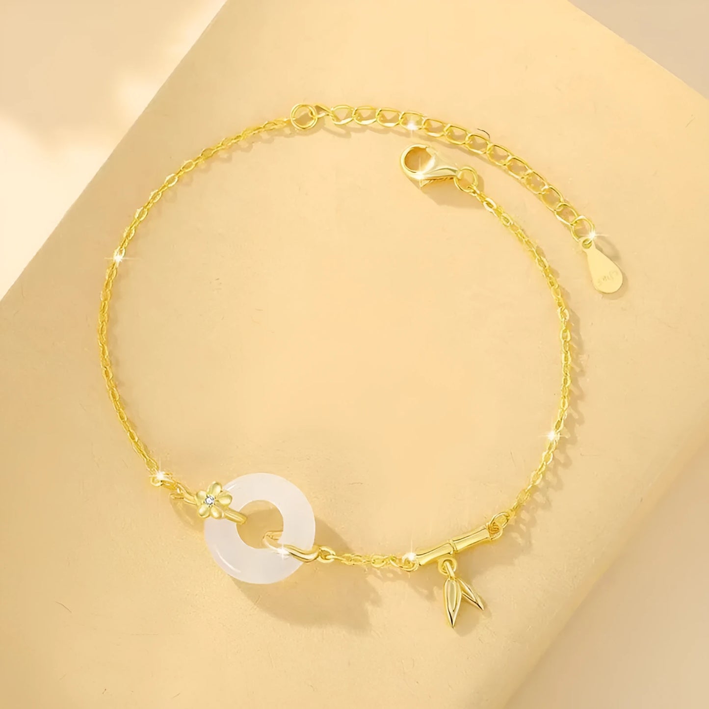 Gold-colour women's bracelet with peace symbol buckle and white chalcedony stone on silver band.