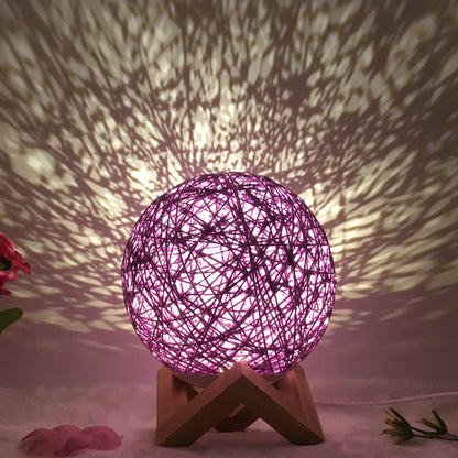 Spherical hand-knitted rattan table lamp with remote control on a wooden desk