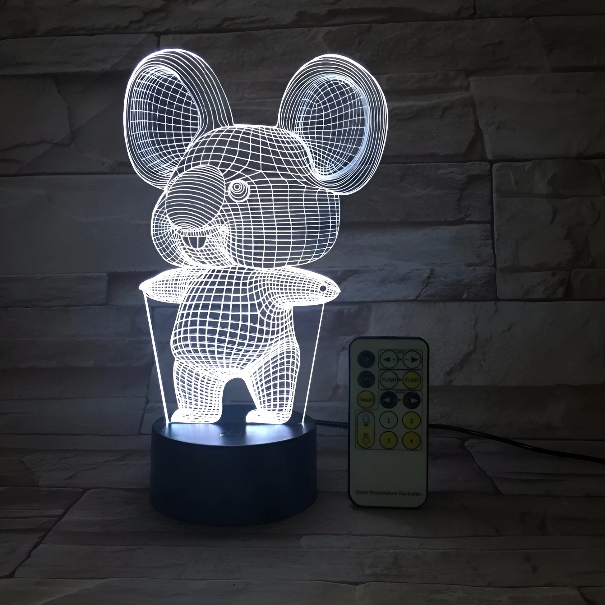 Black Koala night light with LED illumination on a bedside table.