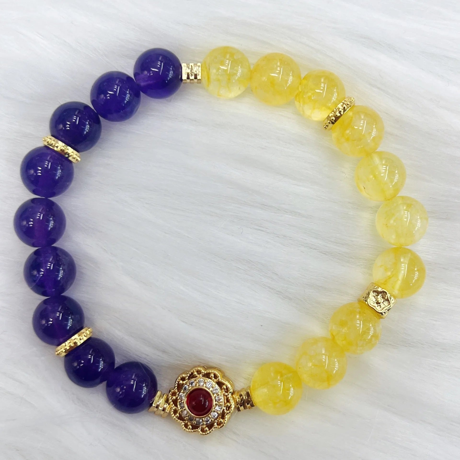 Handmade women's crystal bracelet in yellow and purple colours on a wrist.