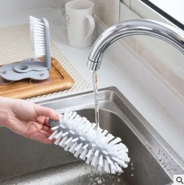 Grey rotating double-head cup brush with suction cups for wall mounting.