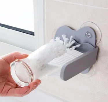 Grey rotating double-head cup brush with suction cups for wall mounting.