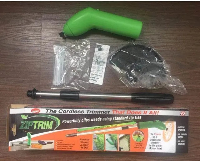 Cordless handheld lawn trimmer with green housing, extension pole, debris shield, and pack of zip ties on a garden lawn.