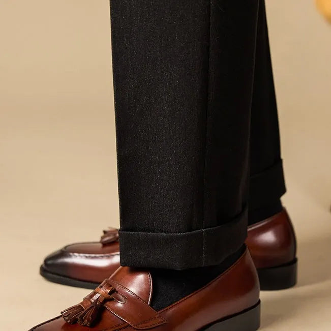 Men's black genuine leather tassel loafers with a rubber sole, shown from a side angle.