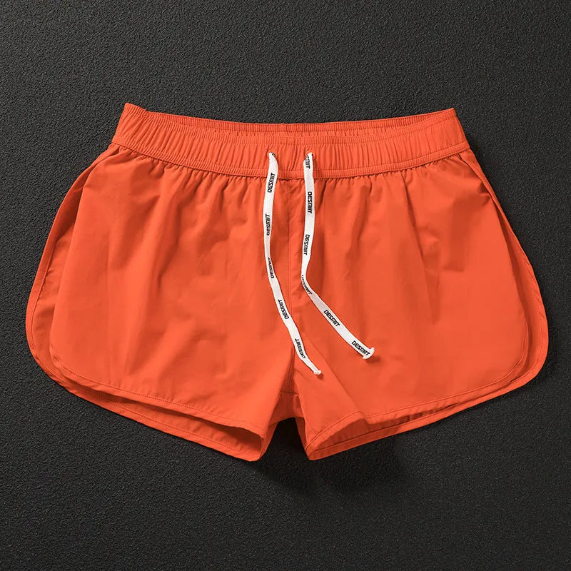 Men's loose orange beach shorts with elastic waist on a sandy shore
