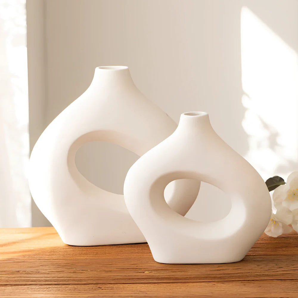 White ceramic circle vase with hand-painted coloured glaze on wooden table with dried flowers