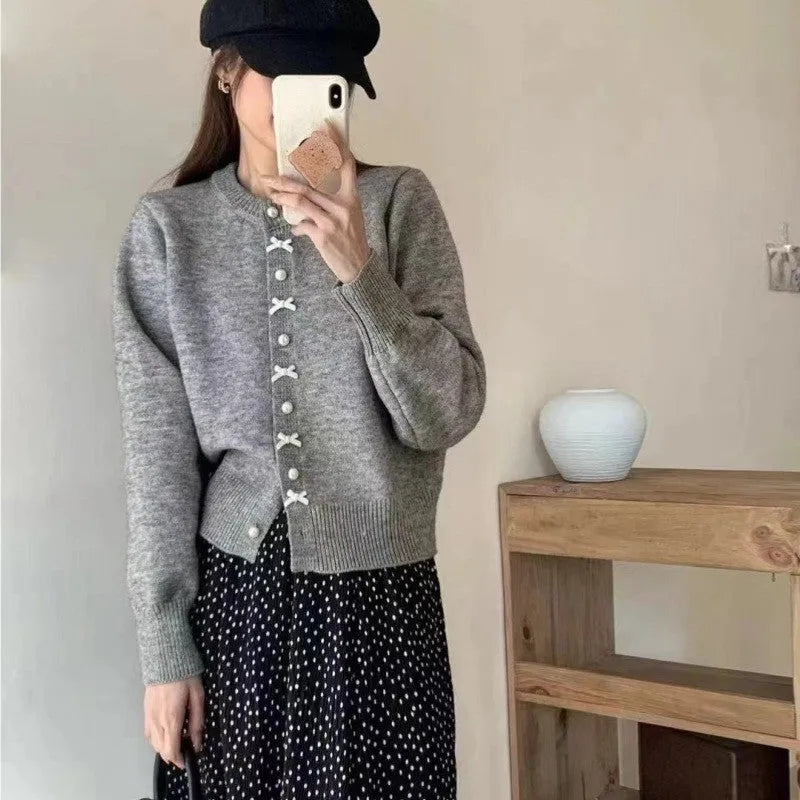 Women's solid colour cardigan sweater with bow pattern and pearl buttons in light blue.