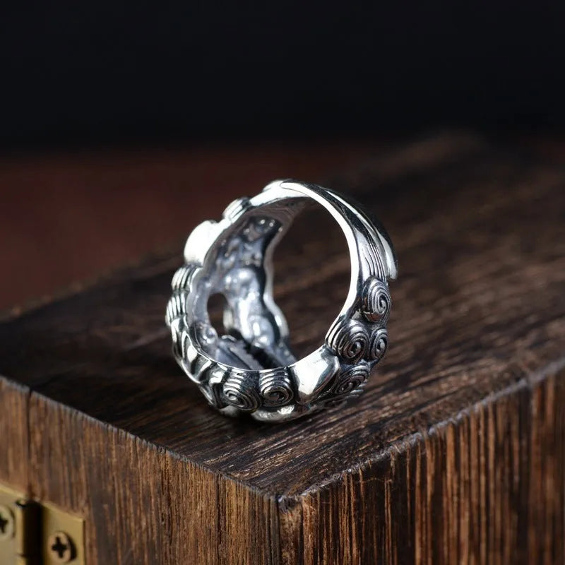 Silver open-style ring with a detailed raised jibeast animal pattern on a model's finger.