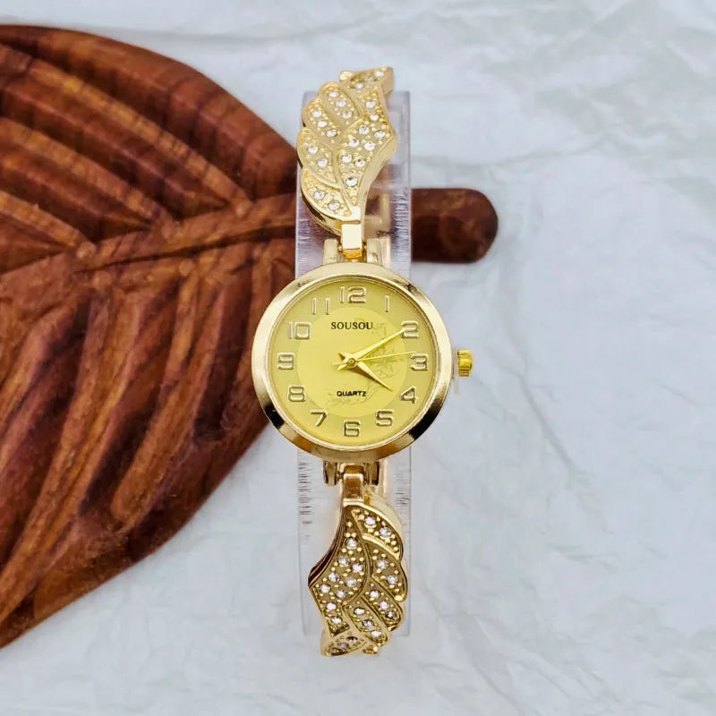 Round stainless steel women's watch on wrist showing gold surface colour and vachette clasp buckle.