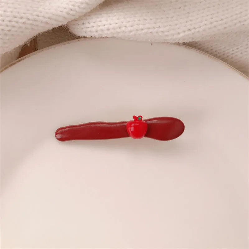 Red plastic hair clip with a 3D love heart and dots on a willow leaf-shaped base.