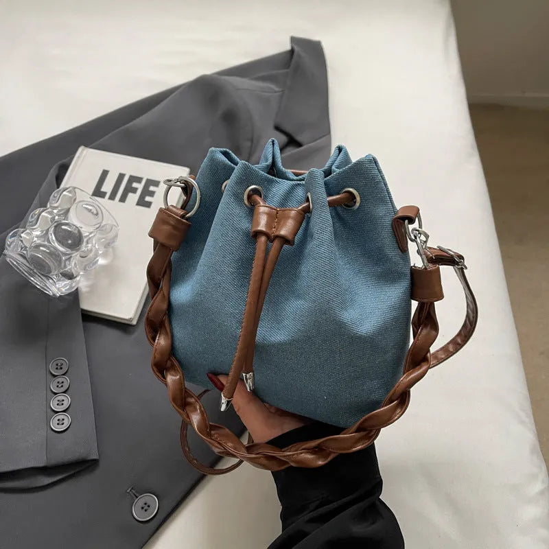 Blue synthetic leather cross body bucket bag with adjustable strap and optional hanging ornaments