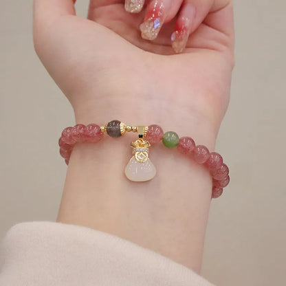 Women's strawberry quartz bracelet with geometric design and decorative purse charm on safety buckle closure