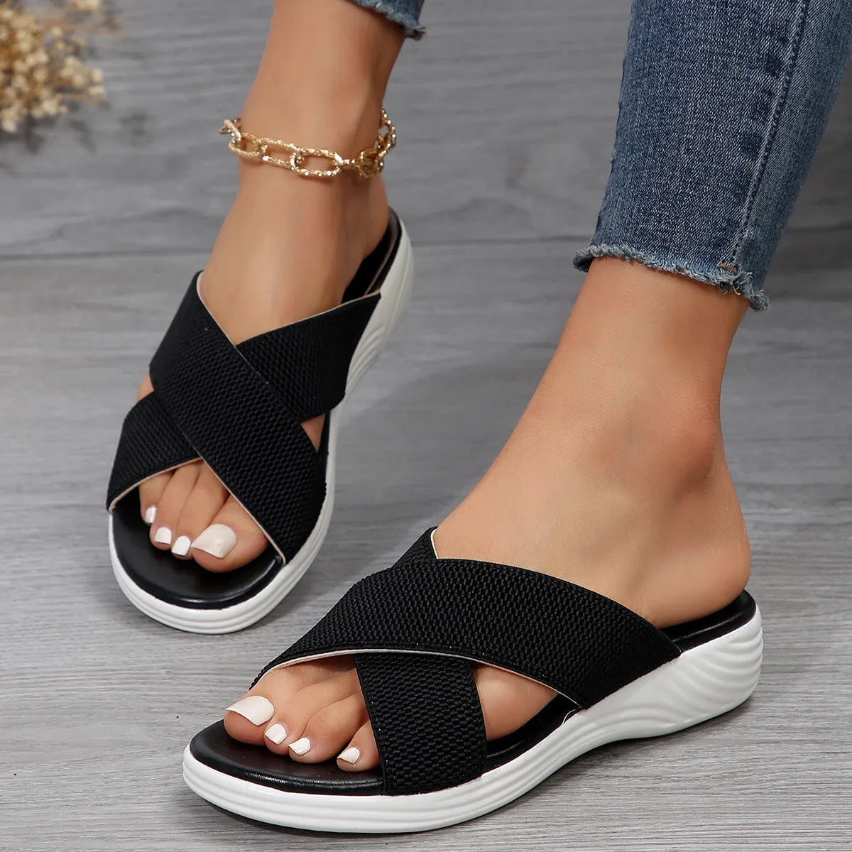 Women's black wedge-heel slippers with peep toe and cross-strap design on a thick rubber sole.