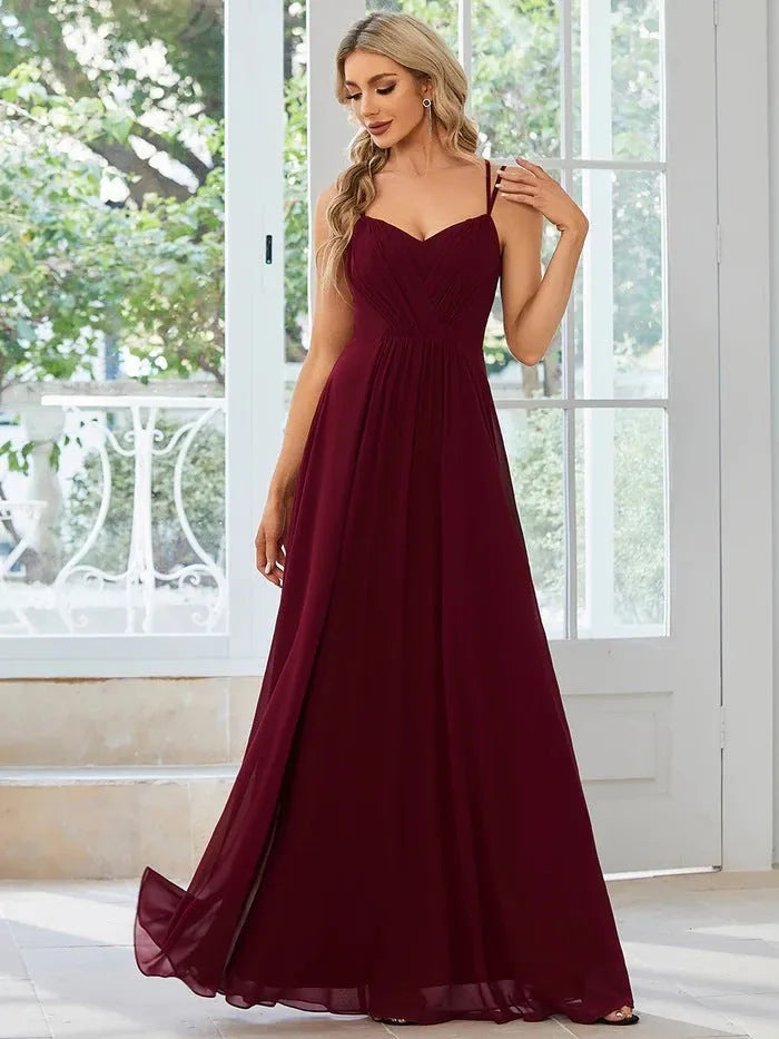 Women's sleeveless long dress with sling neckline and pleated A-line skirt in a solid colour.