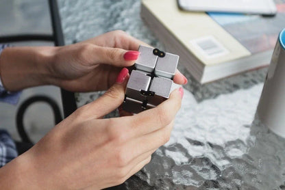 Zinc alloy Infinity Cube with eight rotating cubes showing black and silver colour options on wooden surface