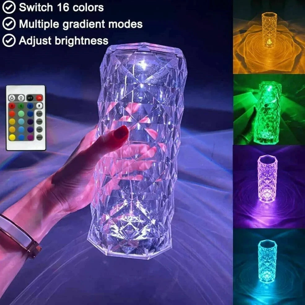 Clear acrylic LED table lamp with diamond-cut surfaces and remote control on wooden surface