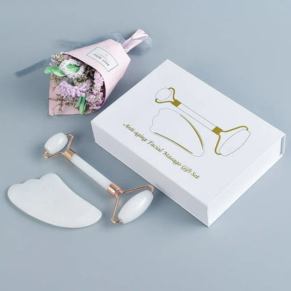 White jade facial roller with double heads and matching scraping board on dark surface