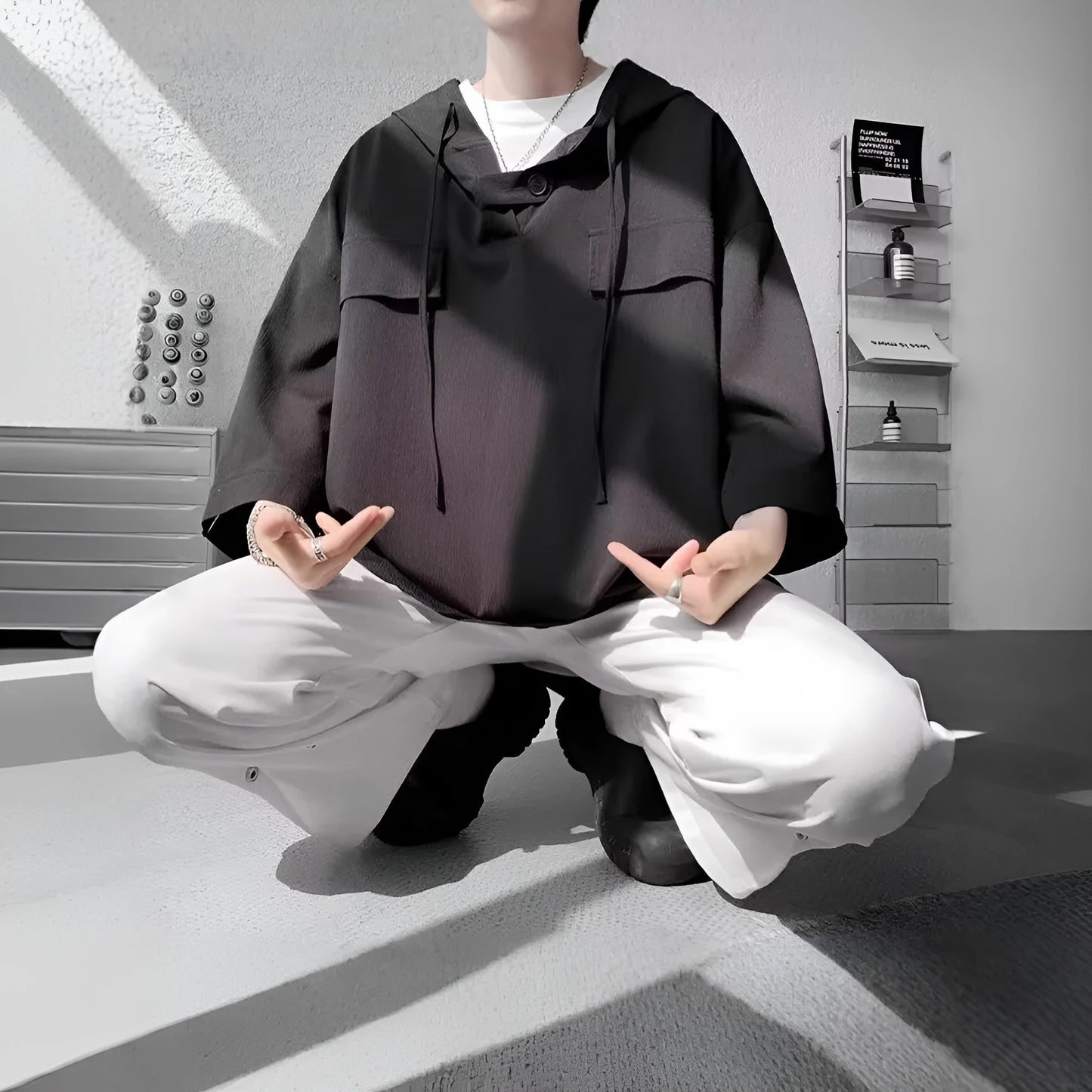 A man wearing a loose-fit black hooded short sleeve t-shirt for summer.