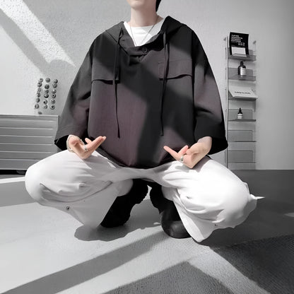 A man wearing a loose-fit black hooded short sleeve t-shirt for summer.