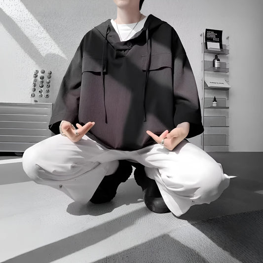 A man wearing a loose-fit black hooded short sleeve t-shirt for summer.