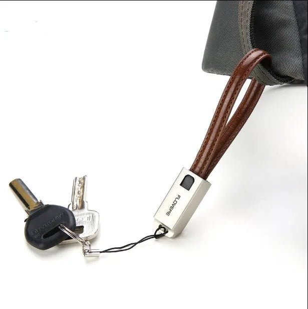 Short black leather iPhone charging cable with metal connector next to a power bank