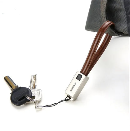 Short black leather iPhone charging cable with metal connector next to a power bank