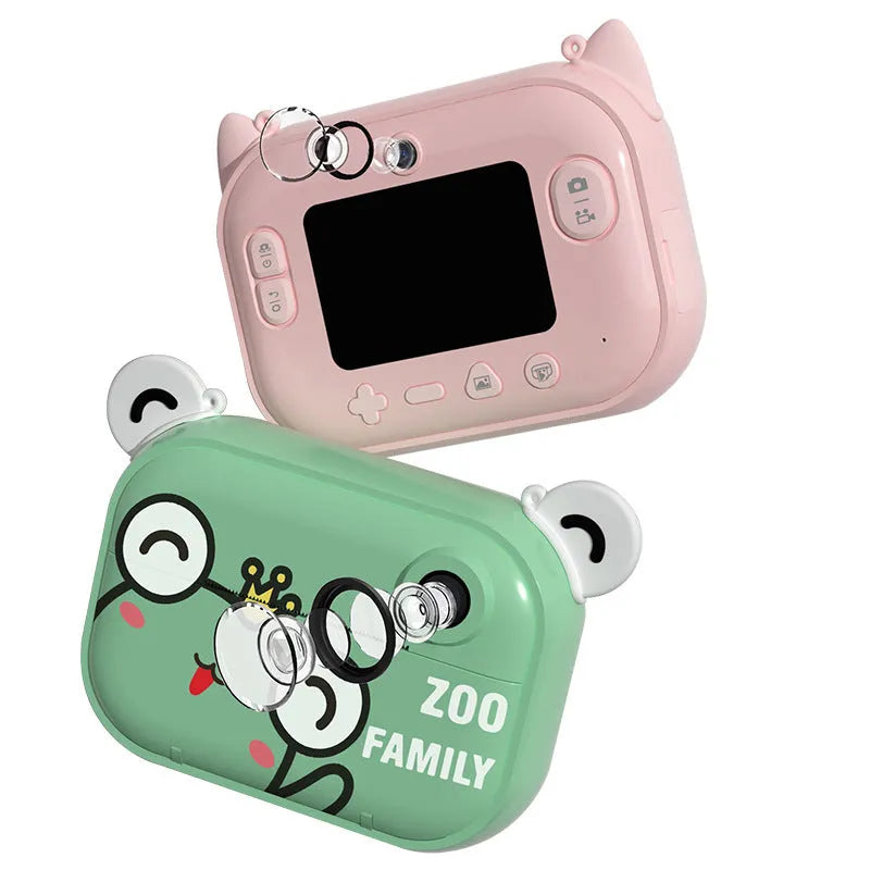 Pink instant print digital camera with LCD screen on a table next to printed photos and accessories.